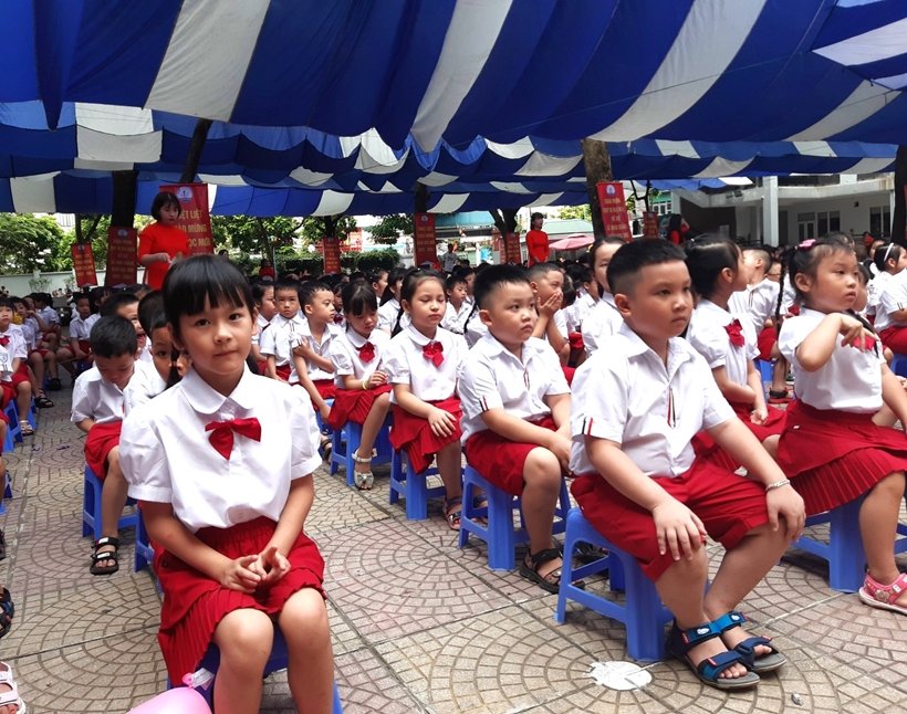 A group of children sitting on chairs under a blue and white tent

Description automatically generated